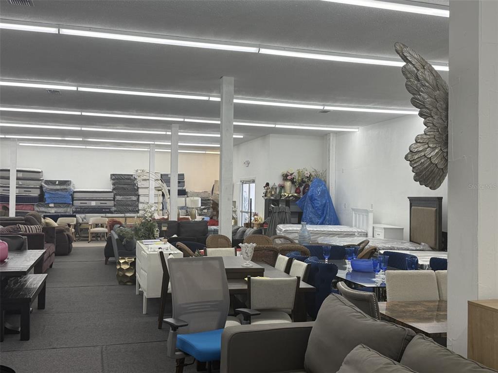 A furniture showroom displays various sofas, dining sets, and stacked mattresses under fluorescent lighting — 2698 S ORANGE BLOSSOM TRAIL, ORLANDO, FL
