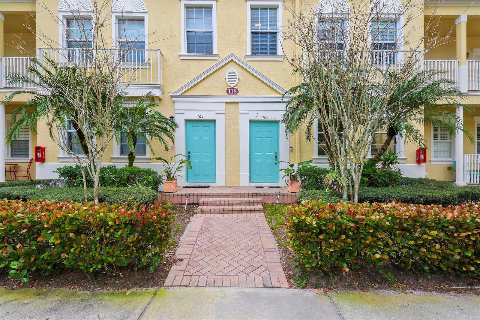 A yellow building exterior features two turquoise front doors labeled 104 and 105 — 118 Seagrape Drive # 105, Jupiter FL 33458, JUPITER, FL