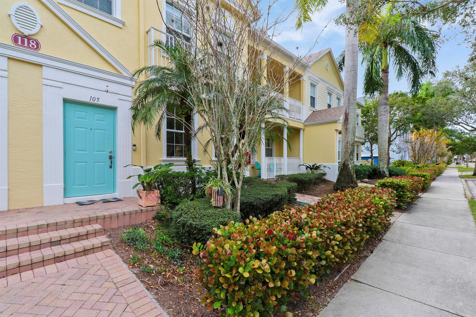 A yellow multi-story building features a teal front door and a landscaped hedge — 118 Seagrape Drive # 105, Jupiter FL 33458, JUPITER, FL