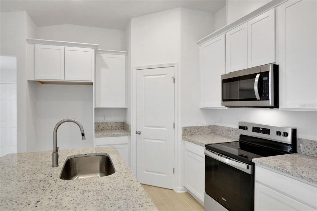 A kitchen features white cabinets, granite countertops, a stainless steel sink, and black appliances — 3889 HOLSTEIN WAY, GREEN COVE SPRINGS, FL