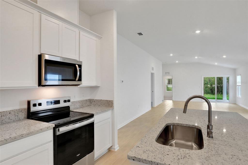 A kitchen with white cabinets, granite countertops, stainless steel appliances, and an island sink — 3889 HOLSTEIN WAY, GREEN COVE SPRINGS, FL