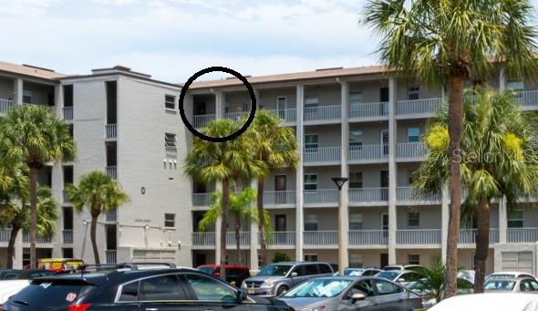 A multi-story apartment building exterior features balconies and a parking lot in the foreground — 3276 LAKE BAYSHORE DRIVE N UNIT O-517, BRADENTON, FL
