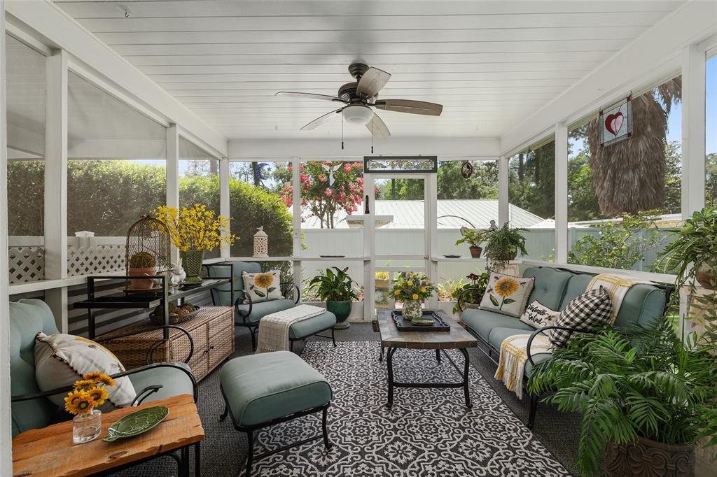 A screened-in porch features a ceiling fan, outdoor furniture, and a patterned area rug — 1807 SW 36TH PLACE, GAINESVILLE, FL