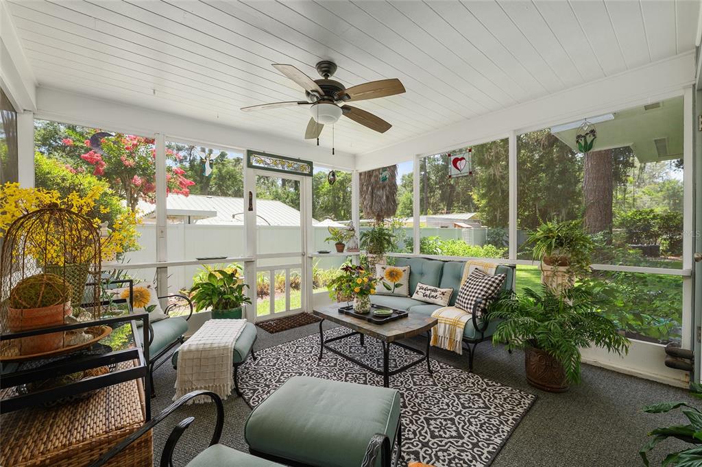 A screened-in porch features a ceiling fan, outdoor furniture, a patterned rug, and potted plants — 1807 SW 36TH PLACE, GAINESVILLE, FL