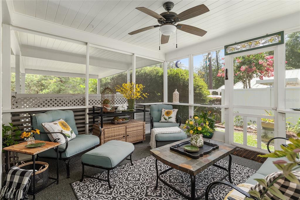 A screened-in porch features light blue cushioned chairs, a patterned rug, and a ceiling fan — 1807 SW 36TH PLACE, GAINESVILLE, FL