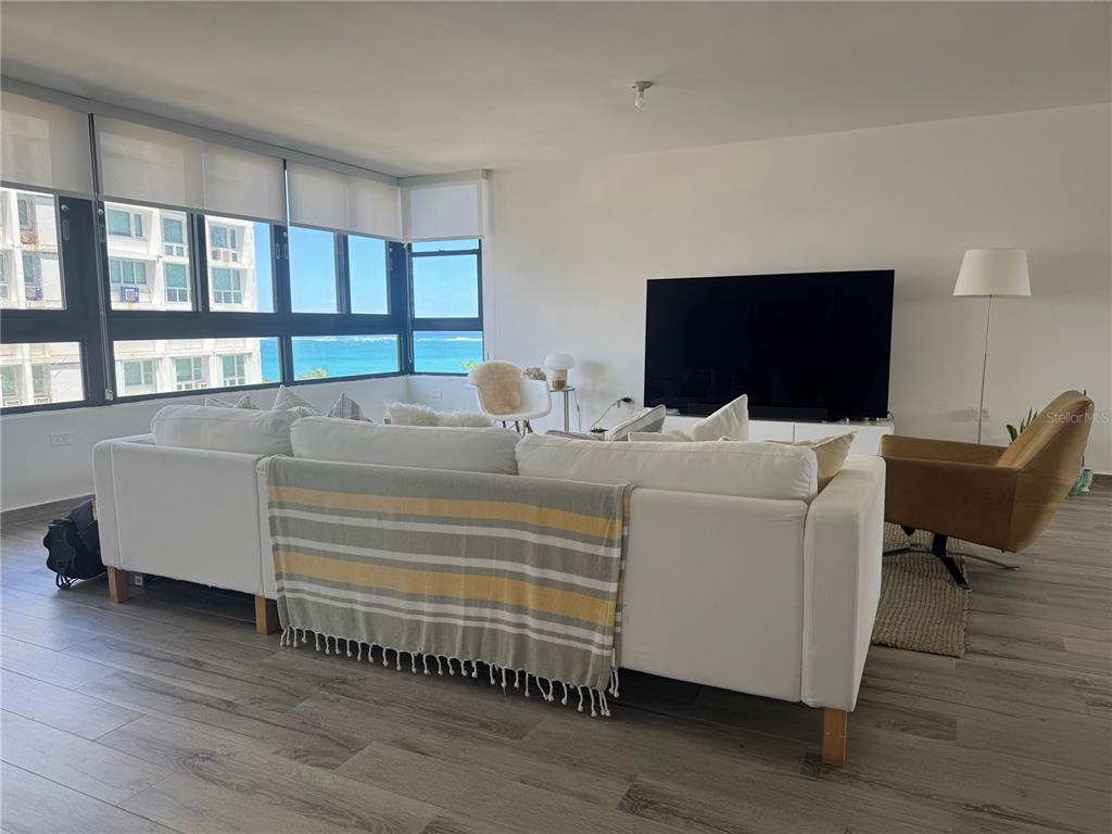 A living room features a white sectional sofa, a large television, and ocean views — 1 TAFT UNIT 7-D, SAN JUAN, PR