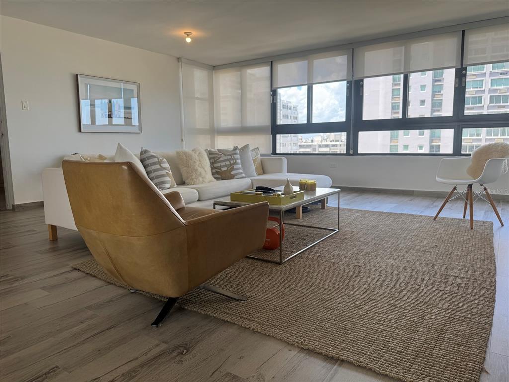 A living room features a white sectional sofa, a tan leather chair, and a jute rug — 1 TAFT UNIT 7-D, SAN JUAN, PR