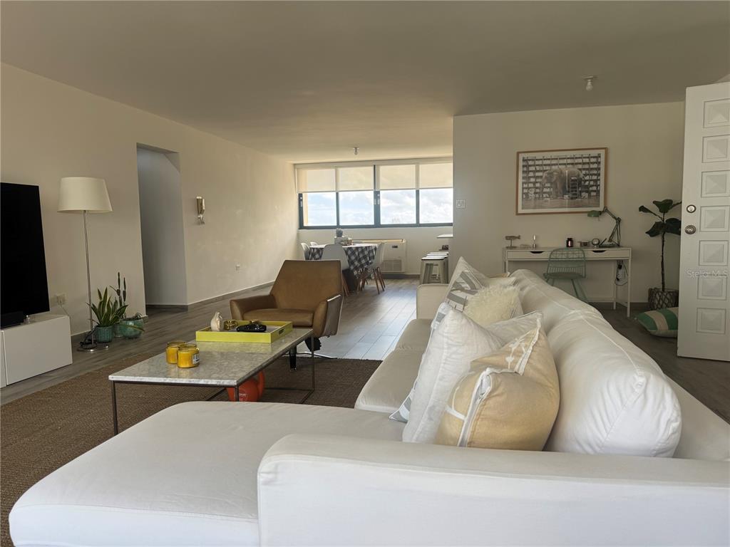 A bright living room features a white sectional sofa, a marble coffee table, and dining area — 1 TAFT UNIT 7-D, SAN JUAN, PR