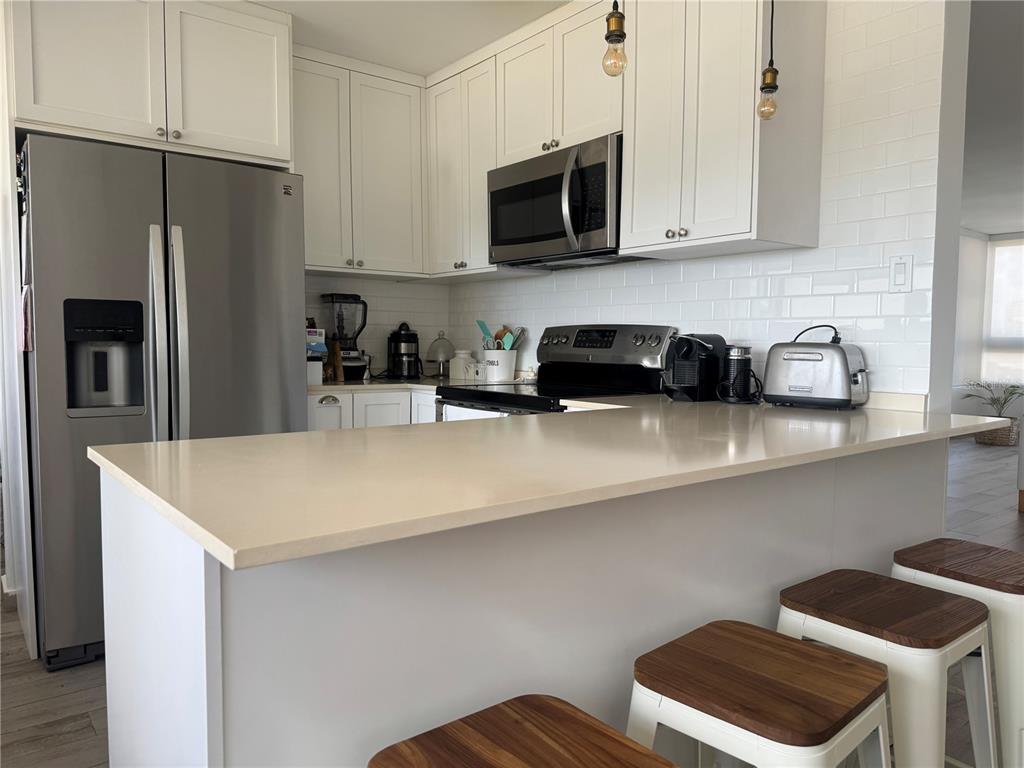 A kitchen features white cabinets, stainless steel appliances, a breakfast bar, and subway tile backsplash — 1 TAFT UNIT 7-D, SAN JUAN, PR