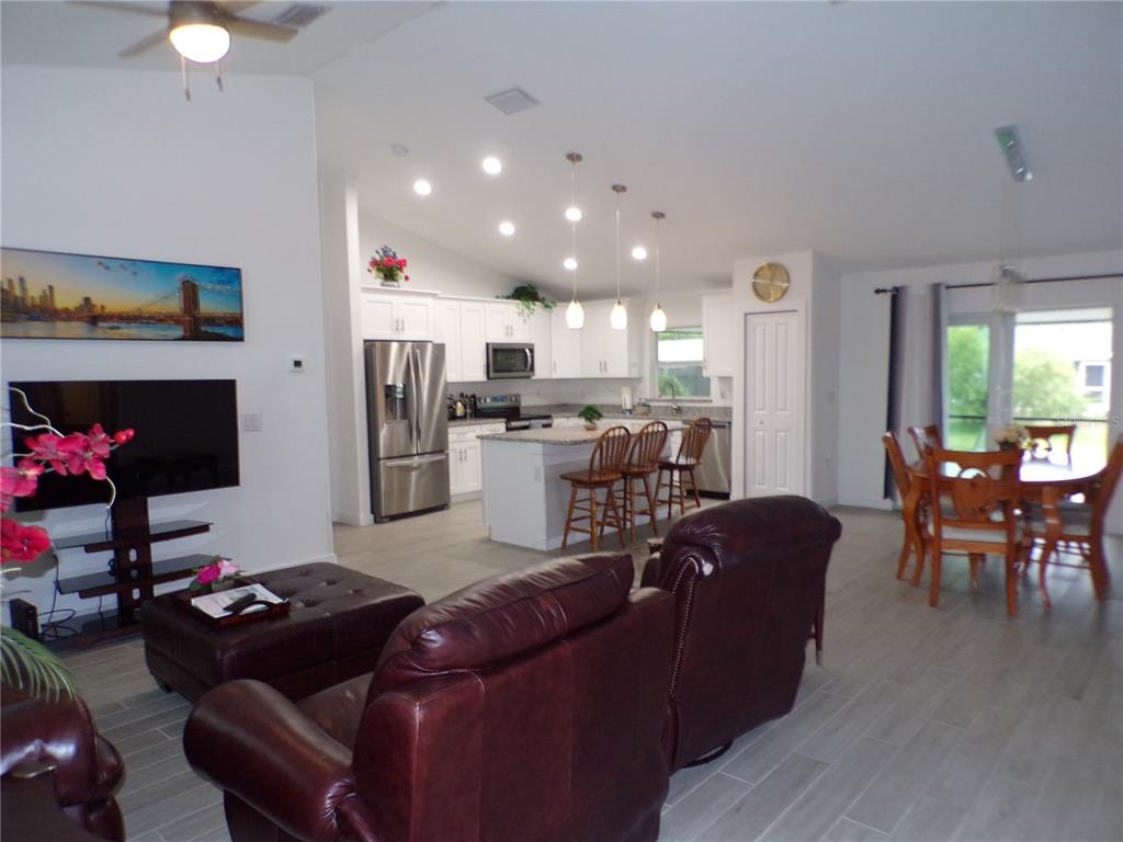 An open-concept living room and kitchen featuring white cabinetry, a center island, and tile flooring — 326 MILLPORT STREET NW, PORT CHARLOTTE, FL