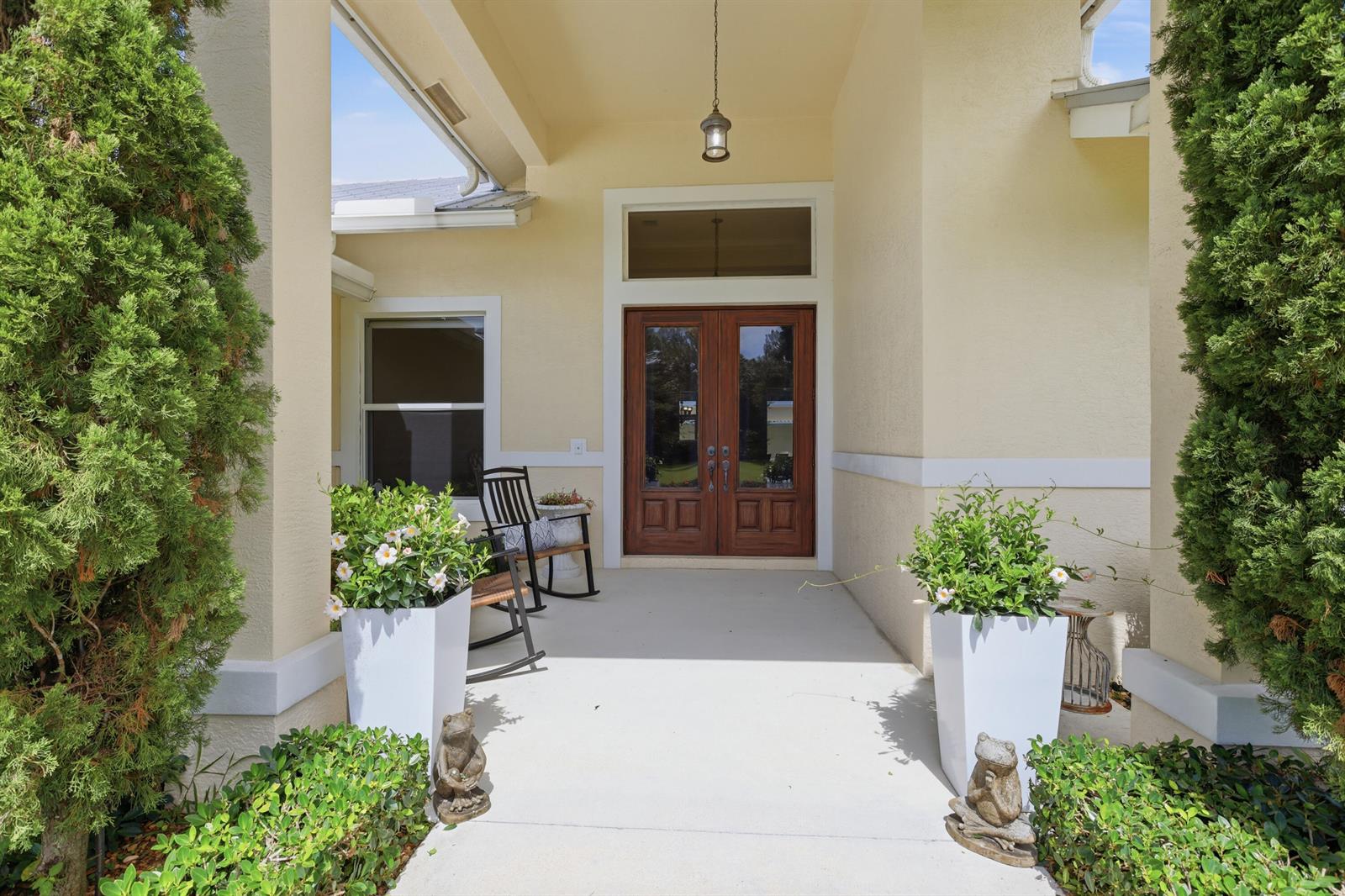 A covered front porch features double wood doors, two rocking chairs, and potted plants — 17593 Winterhawk, Jupiter FL 33478, JUPITER, FL