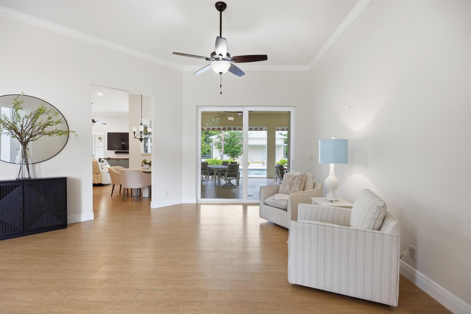 A bright living room features light wood-look flooring, two striped armchairs, and a sliding glass door — 17593 Winterhawk, Jupiter FL 33478, JUPITER, FL
