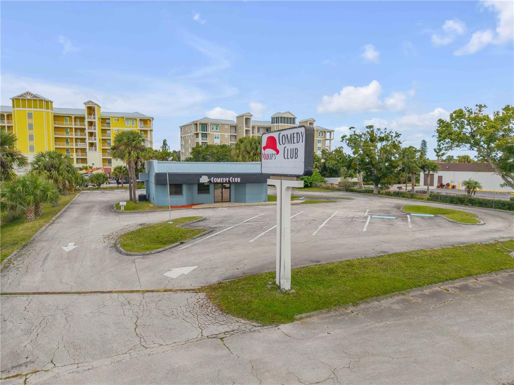 A standalone comedy club building with a parking lot and a prominent street sign — 109 N CAUSEWAY, NEW SMYRNA BEACH, FL