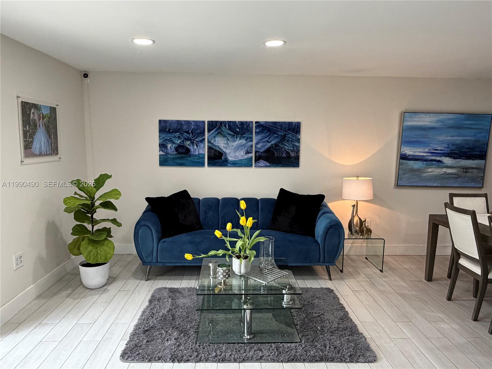 A living room features a blue velvet sofa, glass coffee table, and blue wall art — 7431 SW 163rd Pl, Miami FL 33193, MIAMI, FL