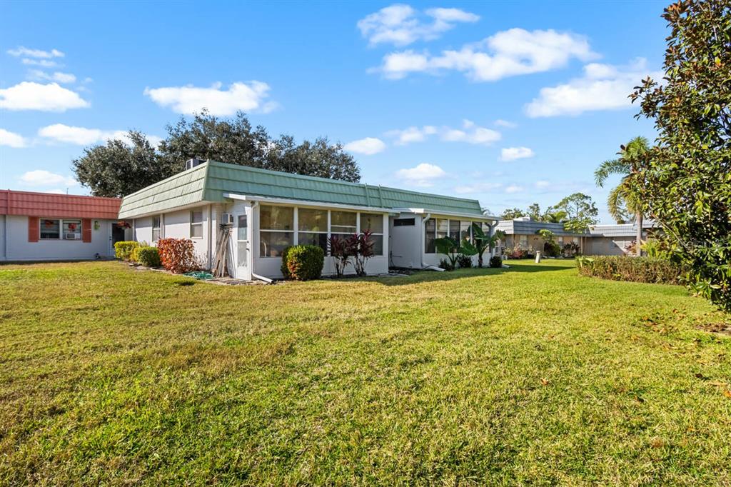 A single-story house with a green mansard roof sits on a large grassy lawn — 1802 BEDFORD LANE UNIT 2, SUN CITY CENTER, FL