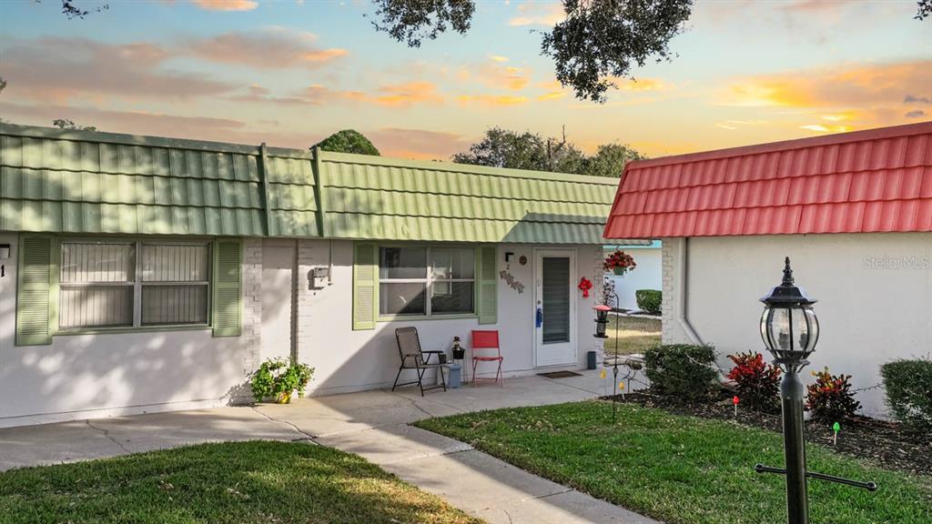 A single-story unit with a green mansard roof, white siding, and a small front patio — 1802 BEDFORD LANE UNIT 2, SUN CITY CENTER, FL
