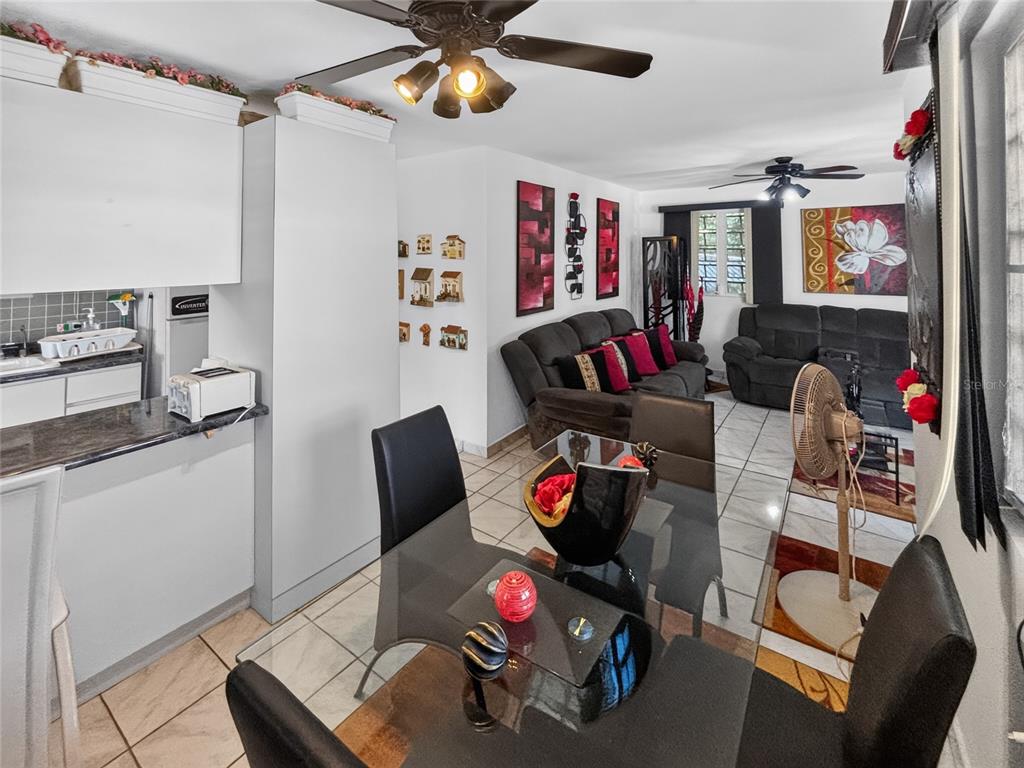 An open-concept living and dining area features white cabinets, tile flooring, and dark furniture — SOLAR S4 BO HIGUILLAR UNIT PARCELA #28, DORADO, PR