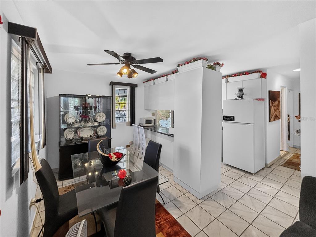 A dining area with a glass table and black chairs adjacent to a white kitchen — SOLAR S4 BO HIGUILLAR UNIT PARCELA #28, DORADO, PR
