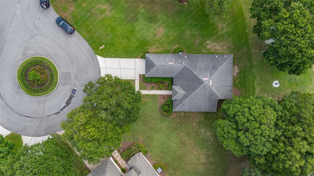 An aerial view shows a house with a gray roof, a driveway, and surrounding trees — 3604 KINGSWOOD COURT, CLERMONT, FL
