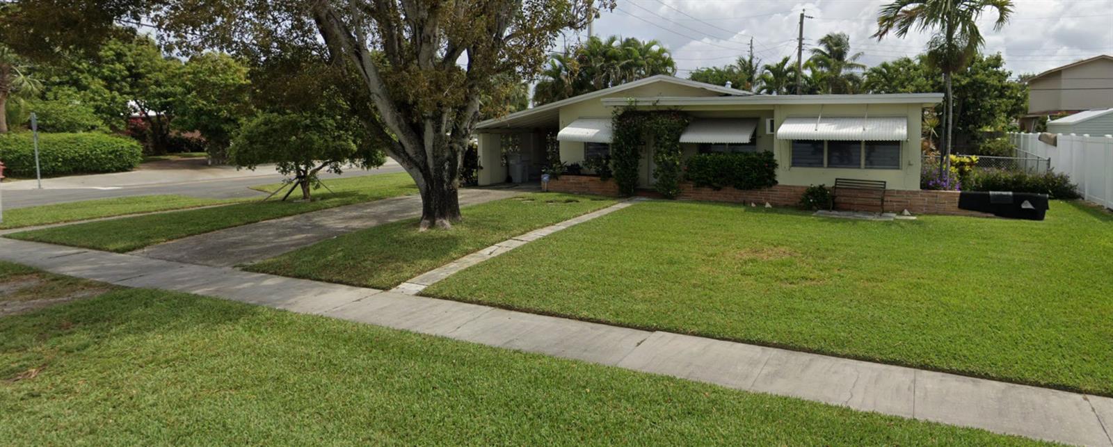 A single-story house with a driveway, a large tree, and a front lawn — 712 NE 23rd Terrace, Pompano Beach FL 33062, POMPANO BEACH, FL