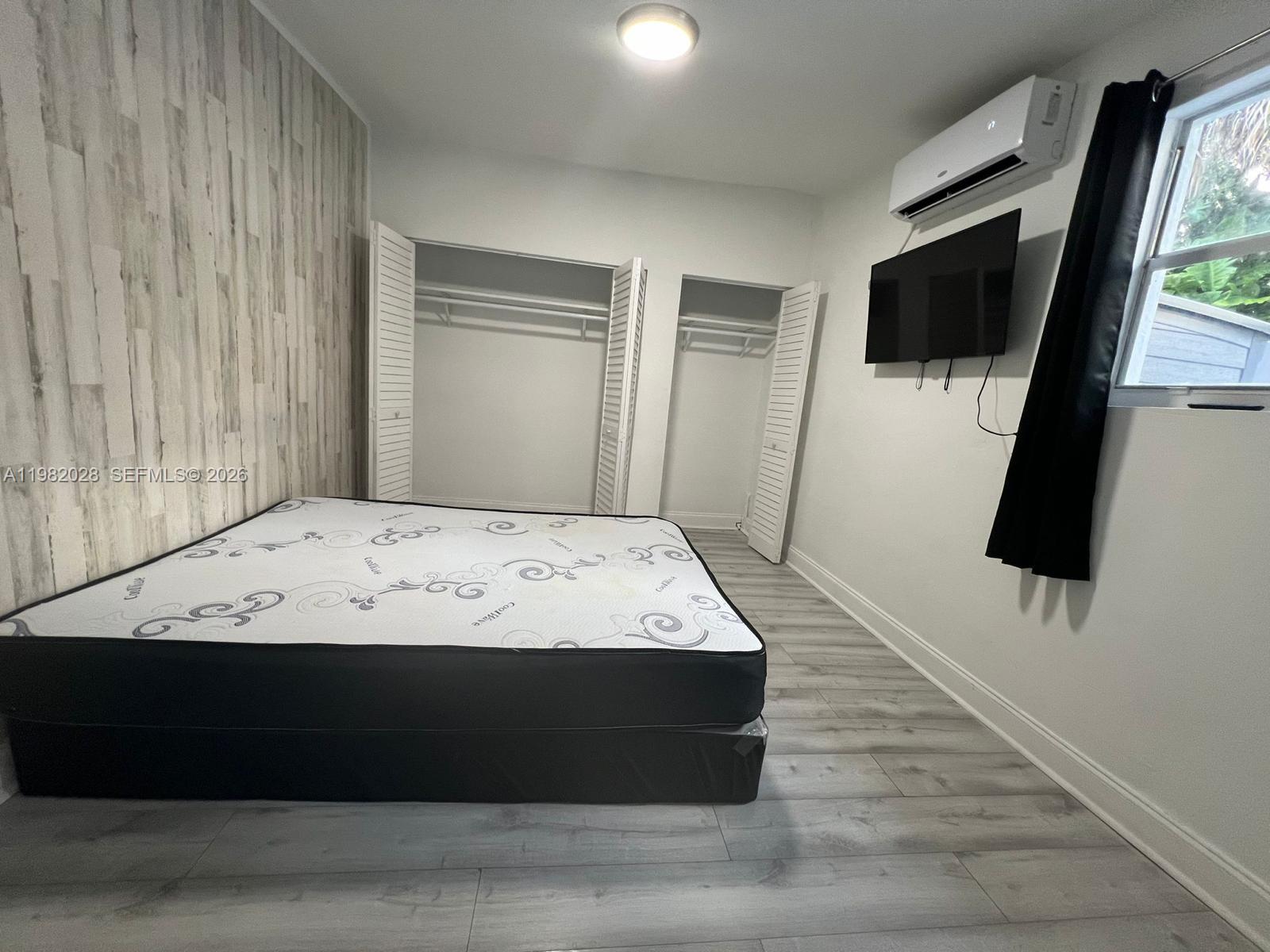 A bedroom features a mattress on the floor, two open closets, and a wall-mounted television — 1053 NE 149th St, Miami FL 33161, MIAMI, FL