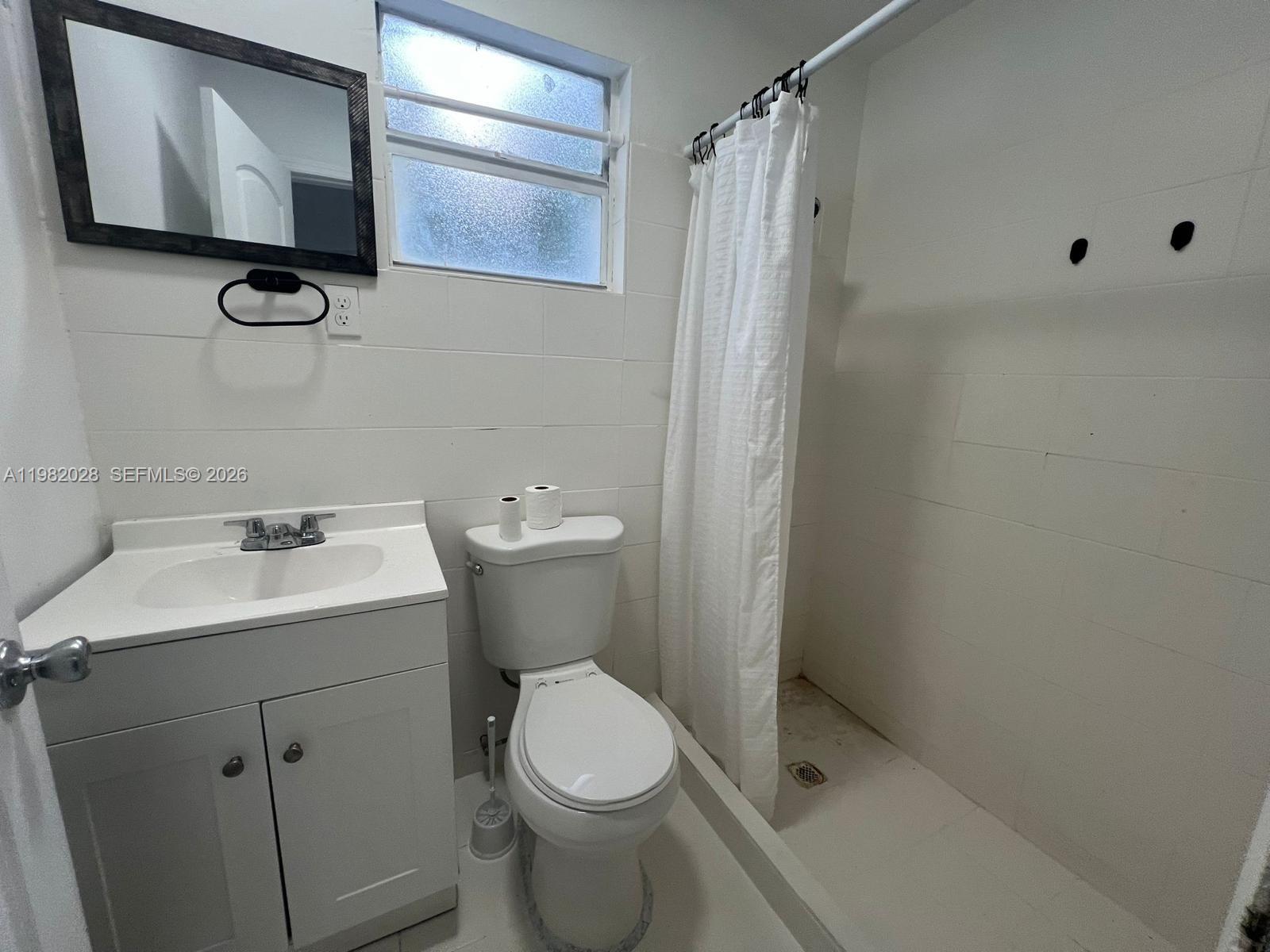 A small bathroom features a white vanity, a toilet, and a walk-in shower — 1053 NE 149th St, Miami FL 33161, MIAMI, FL