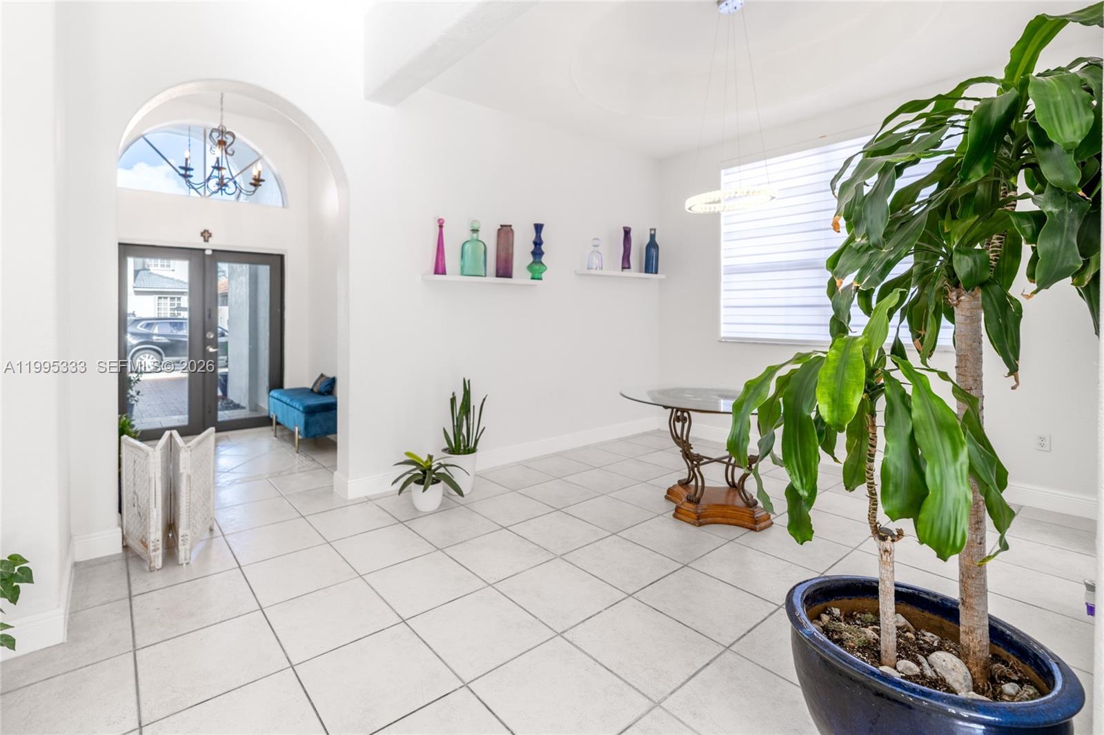 A bright, tiled dining area features a glass table, decorative wall shelves, and a large plant — 3551 SW 152nd Pass, Miami FL 33185, MIAMI, FL