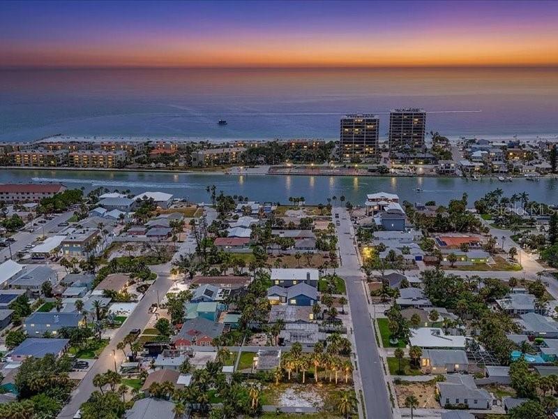 An aerial view of a coastal neighborhood with houses, a waterway, and high-rise buildings — 516 78TH AVENUE, ST PETE BEACH, FL