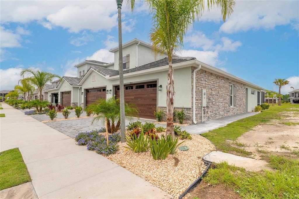 A view of the exterior of a two-story townhouse with a stone facade and garage — 3038 ISLES WAY, NEW SMYRNA BEACH, FL