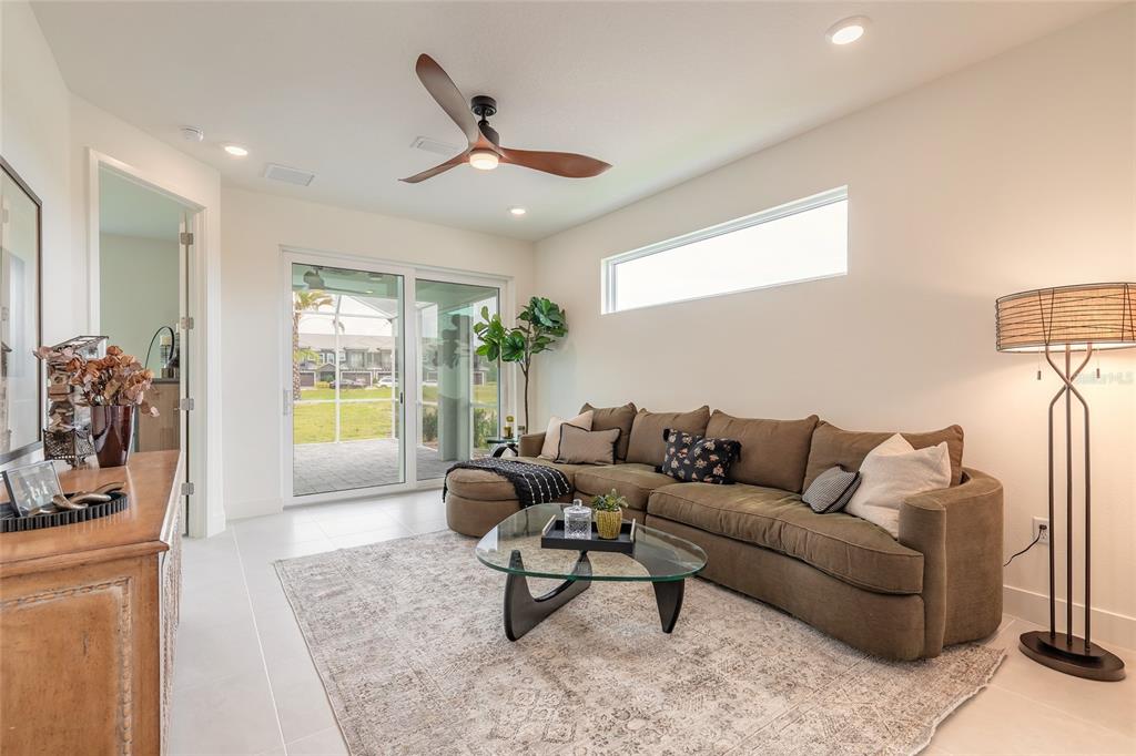 A living room features a brown sectional sofa, glass coffee table, and sliding glass doors — 3038 ISLES WAY, NEW SMYRNA BEACH, FL