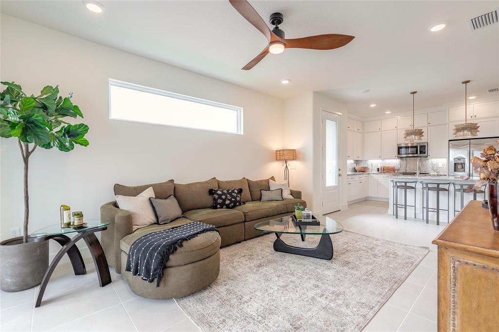 A living room with a sectional sofa, glass coffee table, and an open kitchen — 3038 ISLES WAY, NEW SMYRNA BEACH, FL