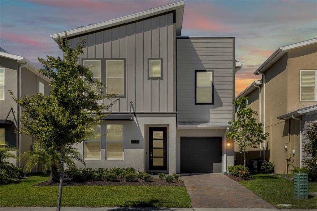 A two-story modern house with a gray facade, a single-car garage, and a paved driveway — 2772 BOOKMARK DRIVE, KISSIMMEE, FL