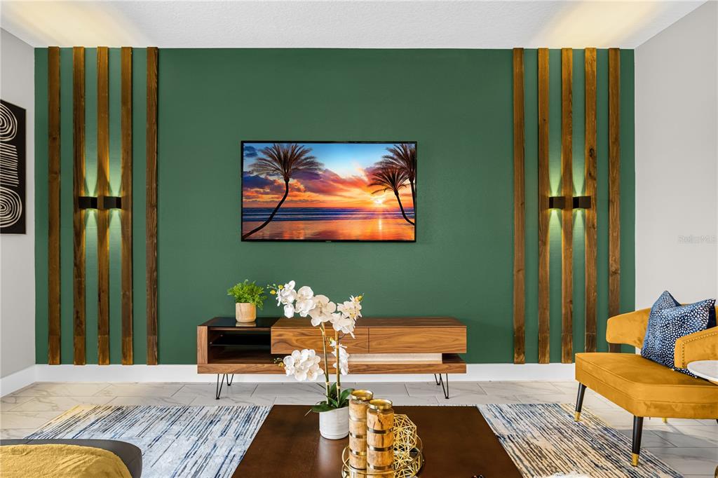 A living room features a green accent wall with wood slats, wall sconces, and television — 2772 BOOKMARK DRIVE, KISSIMMEE, FL