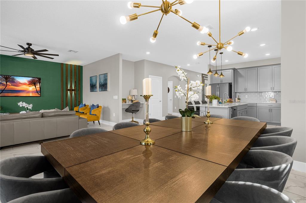 A dining area with a large wooden table leads into an open-concept living room and kitchen — 2772 BOOKMARK DRIVE, KISSIMMEE, FL