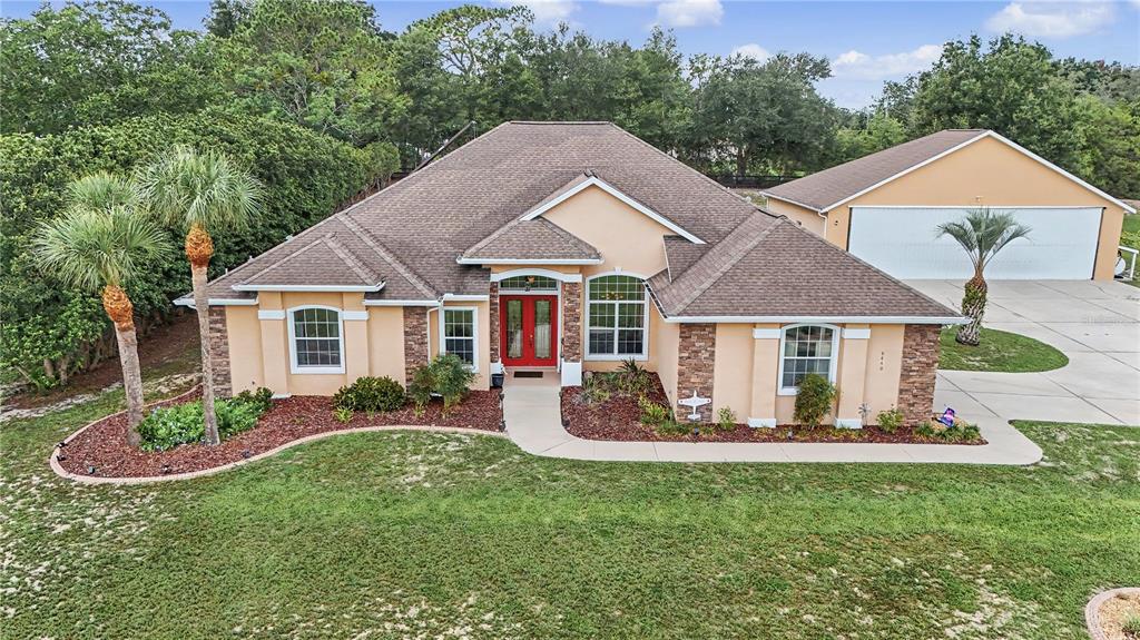 An aerial view of a tan single-story house with a brown roof and detached garage — 8840 SE 70 TERR, OCALA, FL