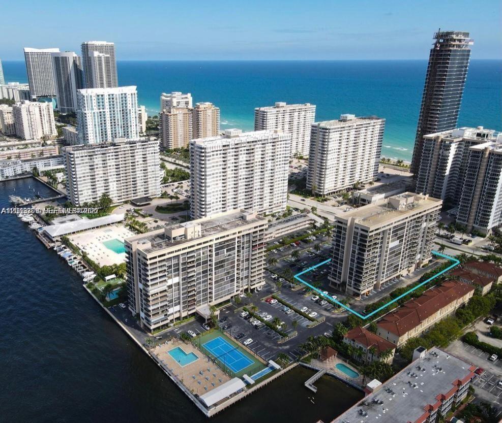 An aerial view shows high-rise apartment buildings along a waterfront with a parking lot — 2049 S Ocean Dr, Hallandale Beach FL 33009, HALLANDALE BEACH, FL