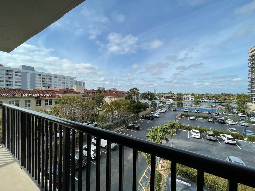 A balcony view overlooks a parking lot, tennis courts, and a waterway with distant buildings — 2049 S Ocean Dr, Hallandale Beach FL 33009, HALLANDALE BEACH, FL