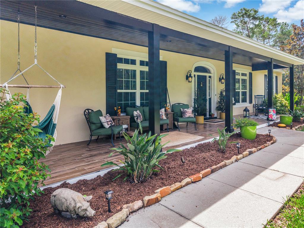 A covered front porch features a hanging chair, outdoor seating, and a tiled floor — 450 VALLEY STREAM DRIVE, GENEVA, FL