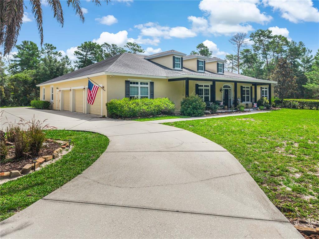 A single-story house with a yellow exterior, a three-car garage, and a concrete driveway — 450 VALLEY STREAM DRIVE, GENEVA, FL