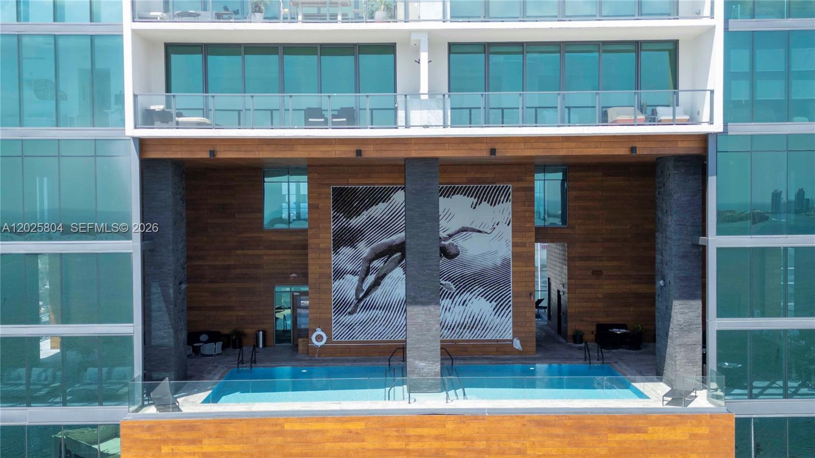 An outdoor swimming pool is situated on a terrace featuring a large wall mural — 1451 Brickell Ave # 2606, Miami FL 33131, MIAMI, FL