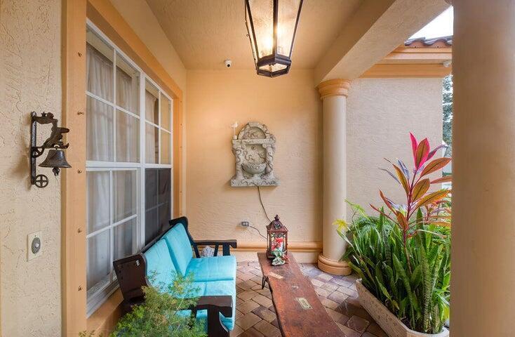 A covered patio features a blue bench, a wall fountain, and a potted plant — 5574 55th Avenue, Vero Beach FL 32967, VERO BEACH, FL