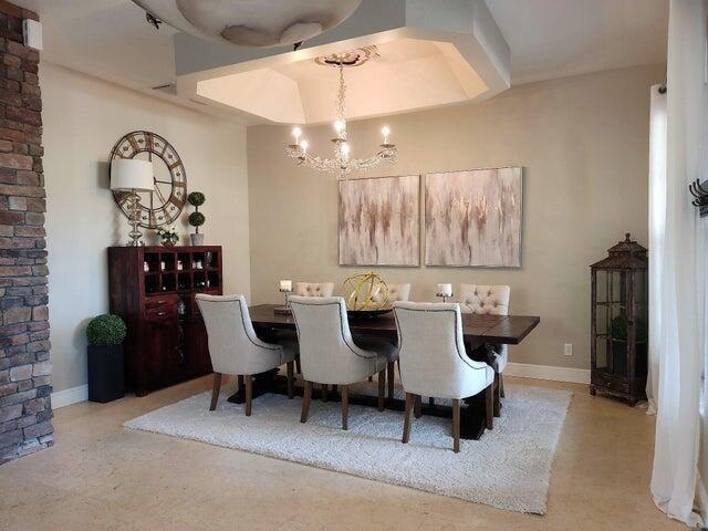 A dining room features a dark wood table, upholstered chairs, a chandelier, and wall art — 5574 55th Avenue, Vero Beach FL 32967, VERO BEACH, FL