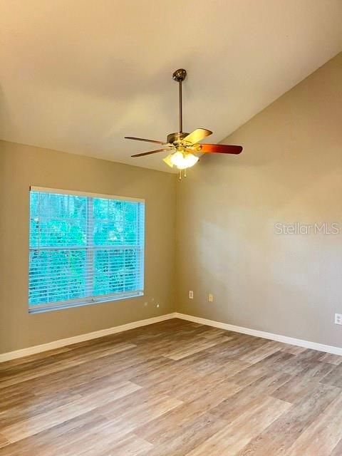 An empty room features light wood-look flooring, beige walls, a ceiling fan, and a window — 970 N SPRING GARDEN AVENUE UNIT 122, DELAND, FL