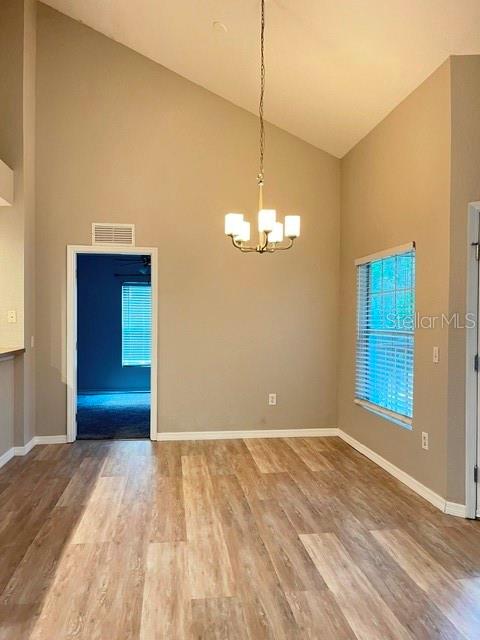 A dining area with wood-look flooring, a vaulted ceiling, a chandelier, and a window — 970 N SPRING GARDEN AVENUE UNIT 122, DELAND, FL