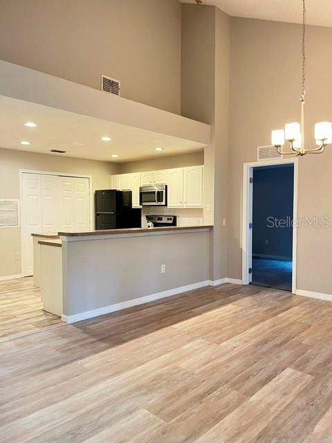 A kitchen with white cabinets and a breakfast bar overlooks a living area — 970 N SPRING GARDEN AVENUE UNIT 122, DELAND, FL