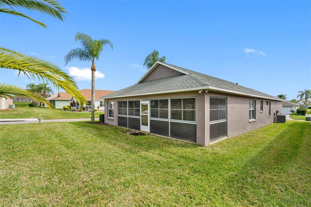 The exterior of a tan house features a screened-in porch and a grassy yard — 3063 WESTMORELAND DRIVE, LAKELAND, FL