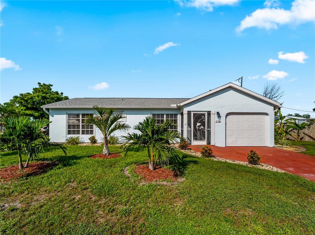 A single-story house with a light blue exterior, a garage, and palm trees in the yard — 119 OLDENBURGH COURT NE, PORT CHARLOTTE, FL