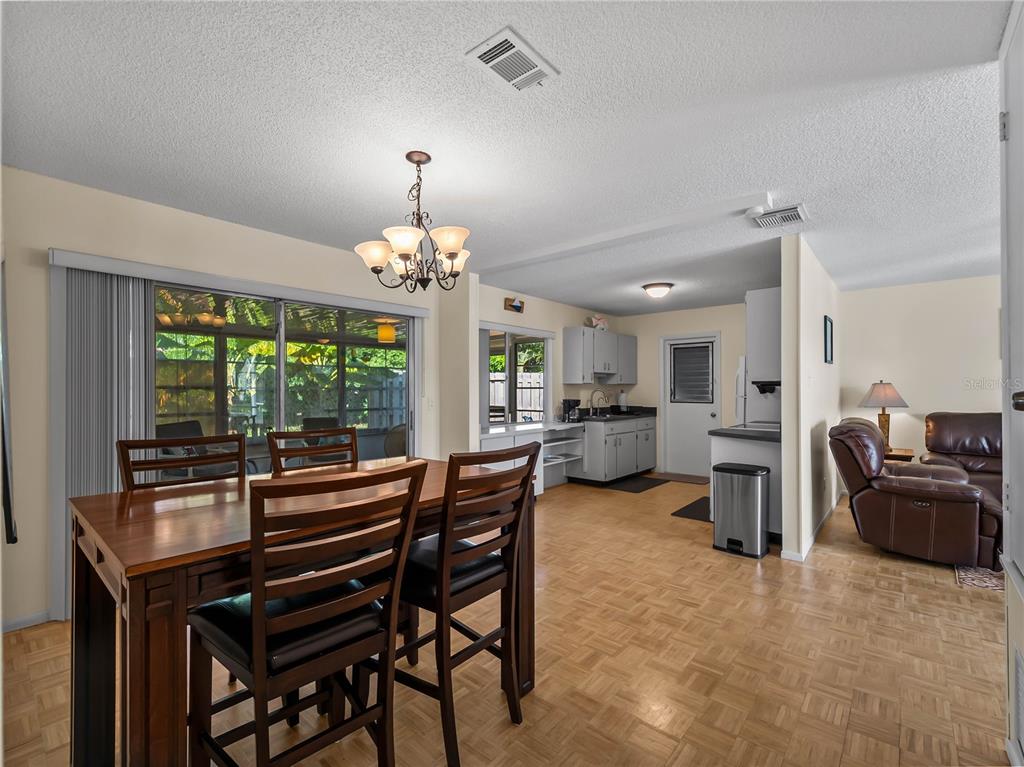 A dining area with a wooden table and chairs opens into a kitchen and living room — 119 OLDENBURGH COURT NE, PORT CHARLOTTE, FL