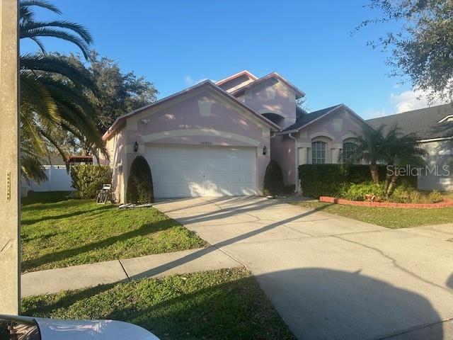 A single-story house with a pink exterior, a two-car garage, and a concrete driveway — 34809 PRAIRIE RIDGE WAY, ZEPHYRHILLS, FL