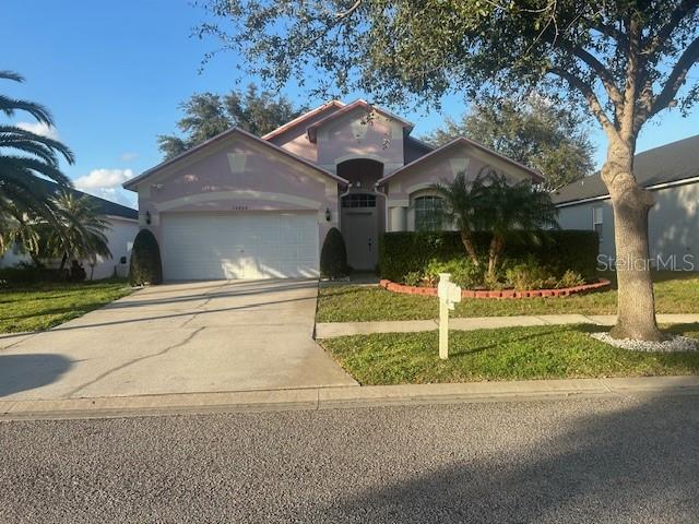A light pink single-story house with a two-car garage and a landscaped front yard — 34809 PRAIRIE RIDGE WAY, ZEPHYRHILLS, FL